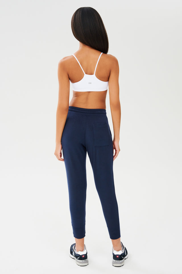 The back view of a woman wearing navy sweatpants and a Splits59 Loren Seamless Bra - White, ready for gym workouts.