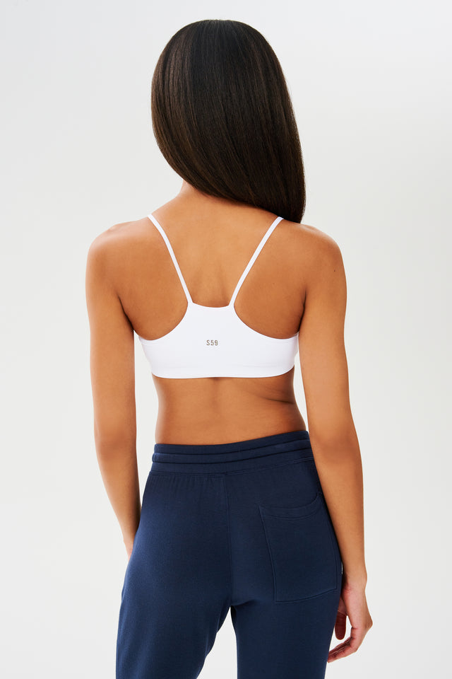 The back view of a woman wearing a Splits59 Loren Seamless Bra in White and navy sweatpants, perfect for chafe-free gym workouts.
