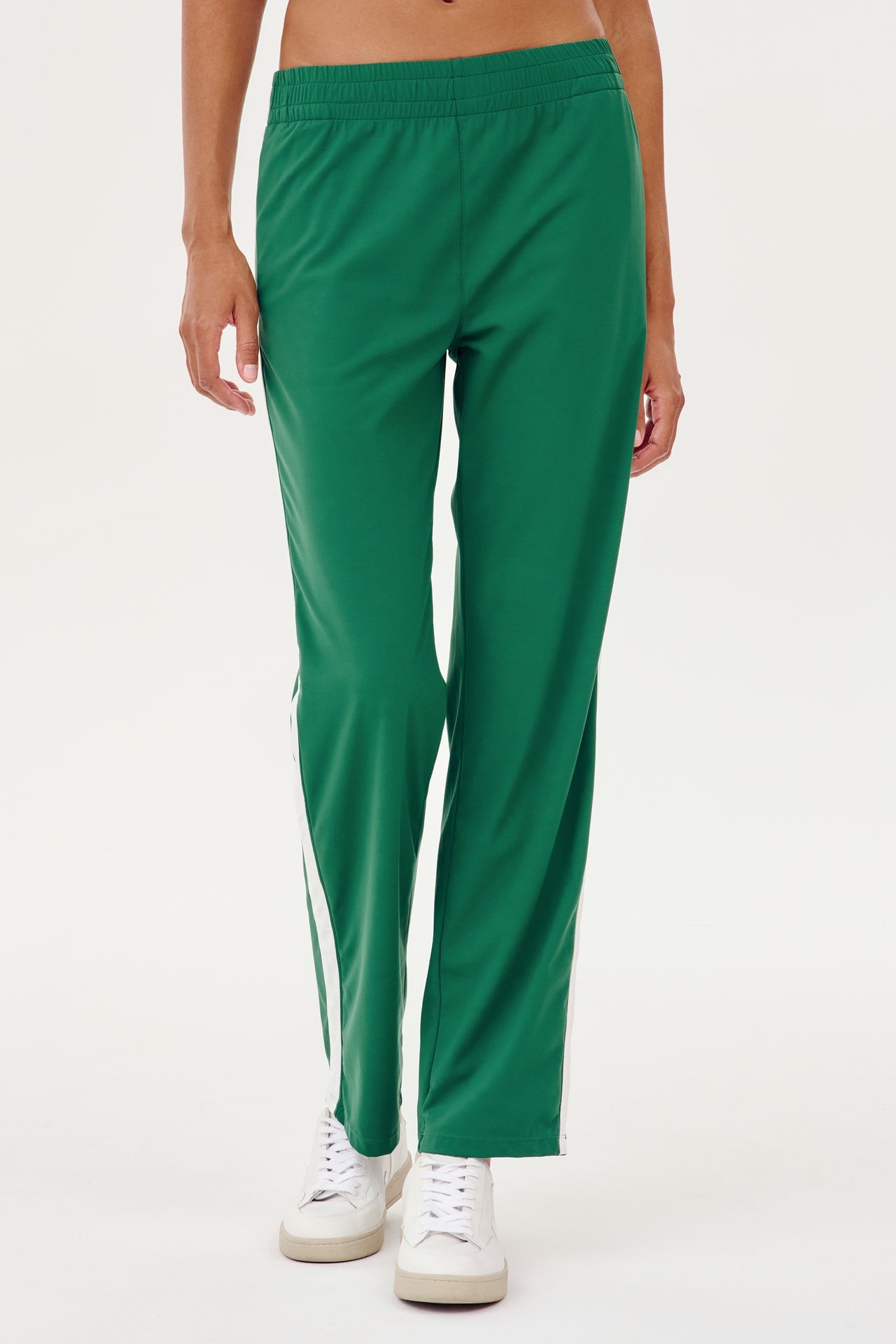 A woman wearing SPLITS59 Max Rigor Track Pant in Arugula/White for outdoor workouts.