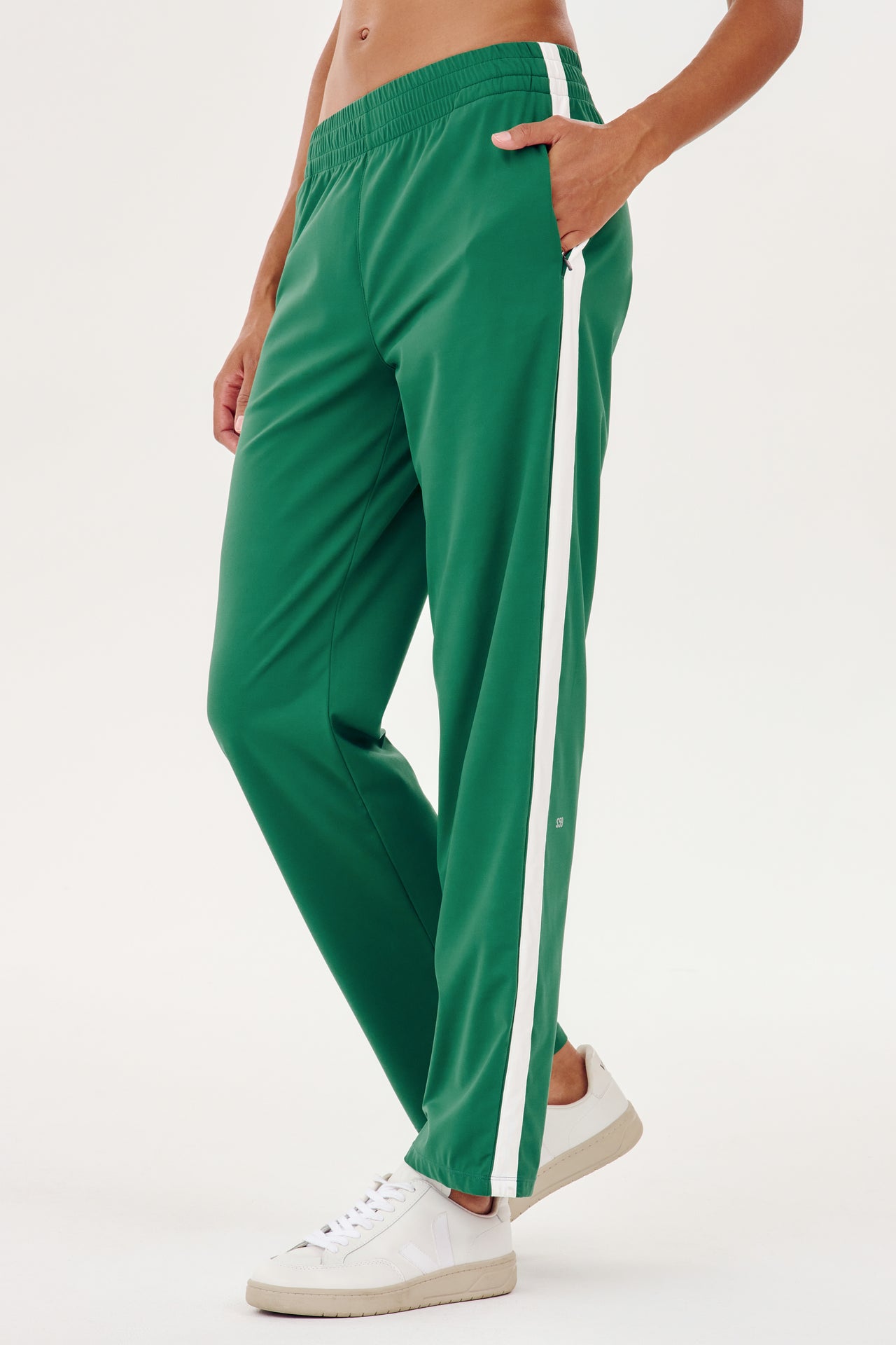 A woman wearing SPLITS59's Max Rigor Track Pant in Arugula/White designed for outdoor workouts.