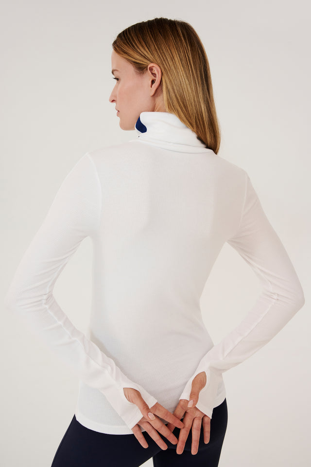 The back view of a woman wearing a SPLITS59 Jackson Rib Full Length Turtleneck in White/Indigo suitable for yoga.