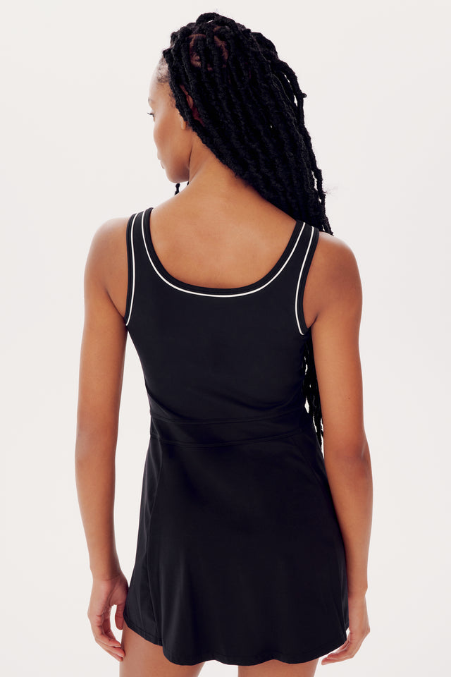 Rear view of a woman in a black Splits59 Martina Rigor Dress W/Piping, featuring braided hair, isolated on a white background.