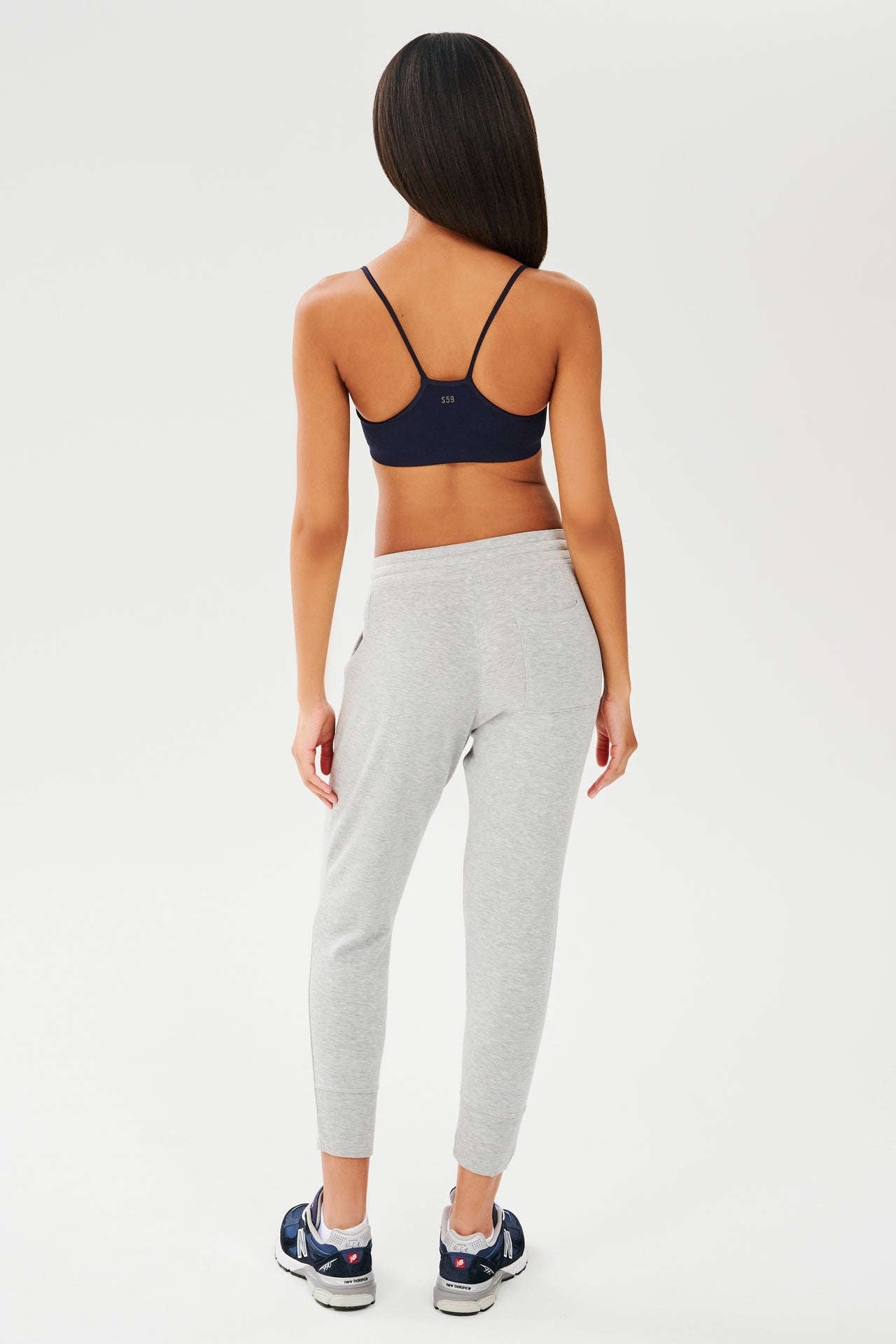 The back view of a woman wearing a SPLITS59 Loren Seamless Bra in Indigo and joggers.