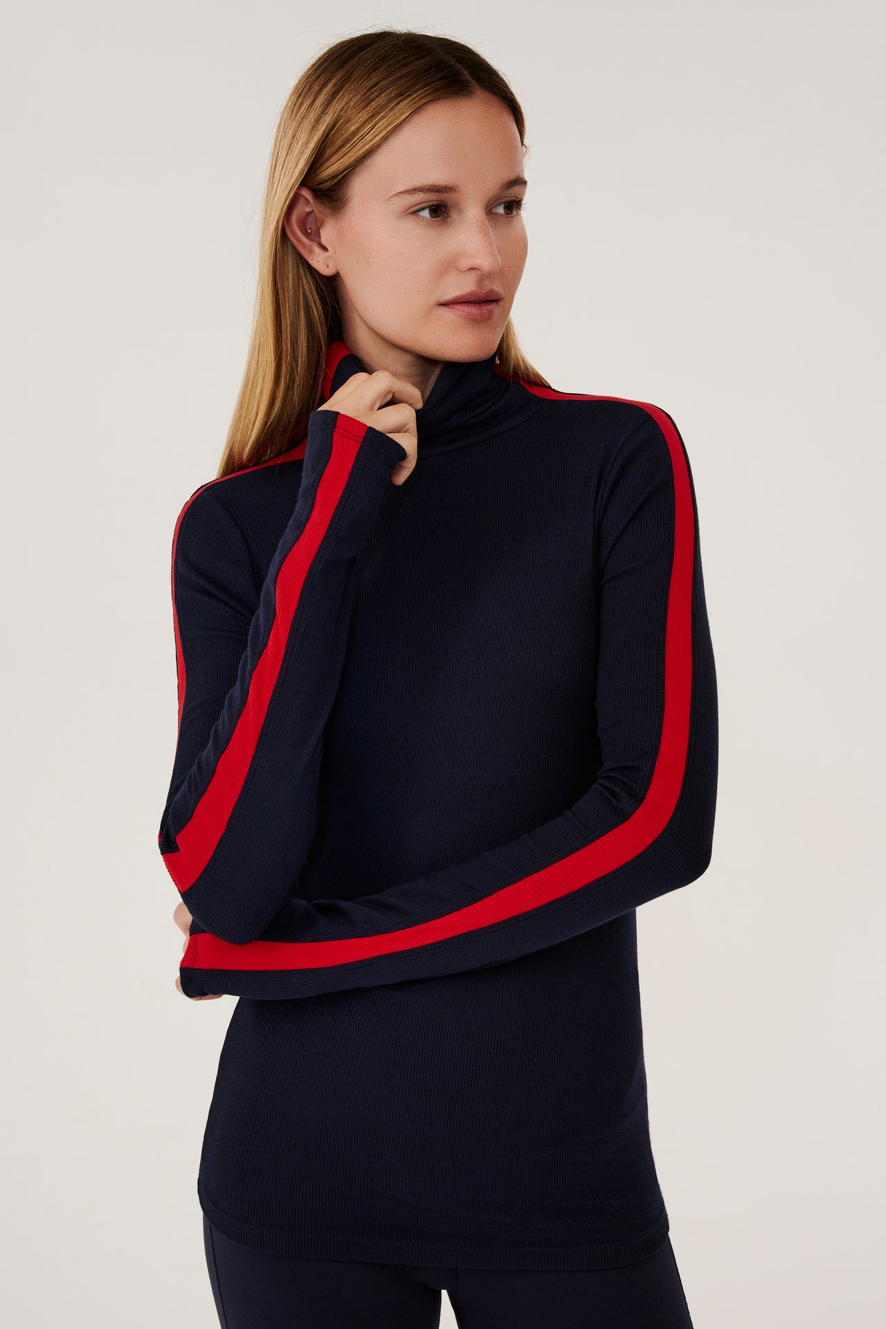A woman wearing a Jackson Rib Full Length Turtleneck in Indigo/Pirate Red by SPLITS59 with red and blue stripes.