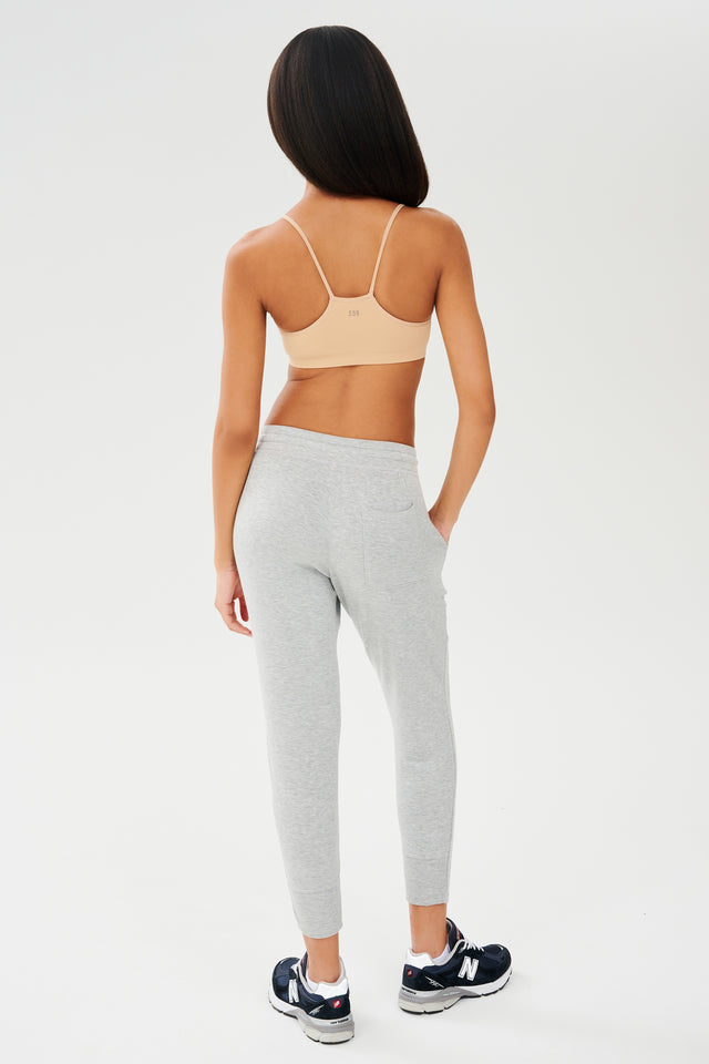 The back view of a woman wearing a Splits59 Loren Seamless Bra - Nude and joggers.