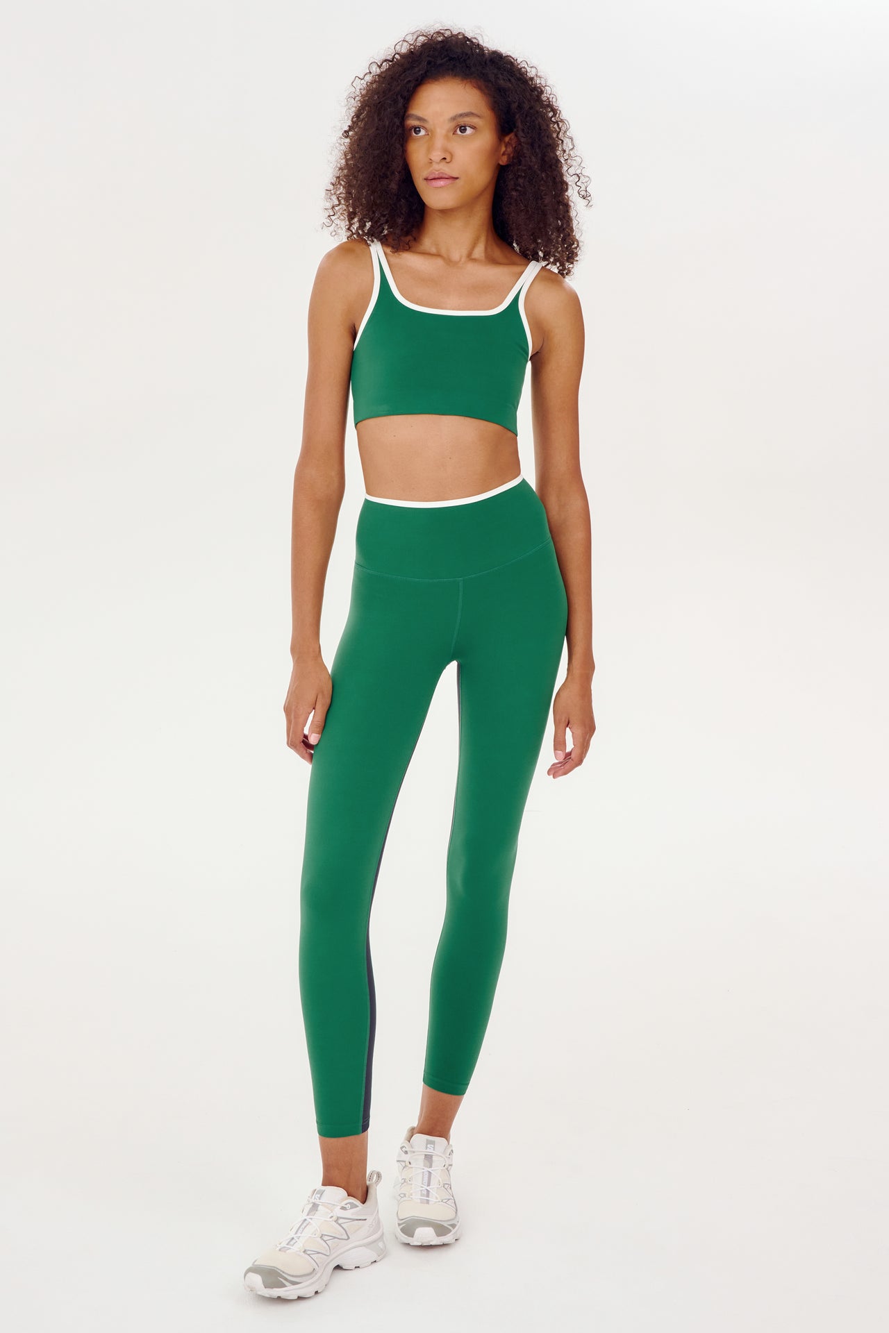 A woman wearing SPLITS59's Easton Rigor High Waist 7/8 - Arugula/White sports bra and leggings, perfect for gym workouts.