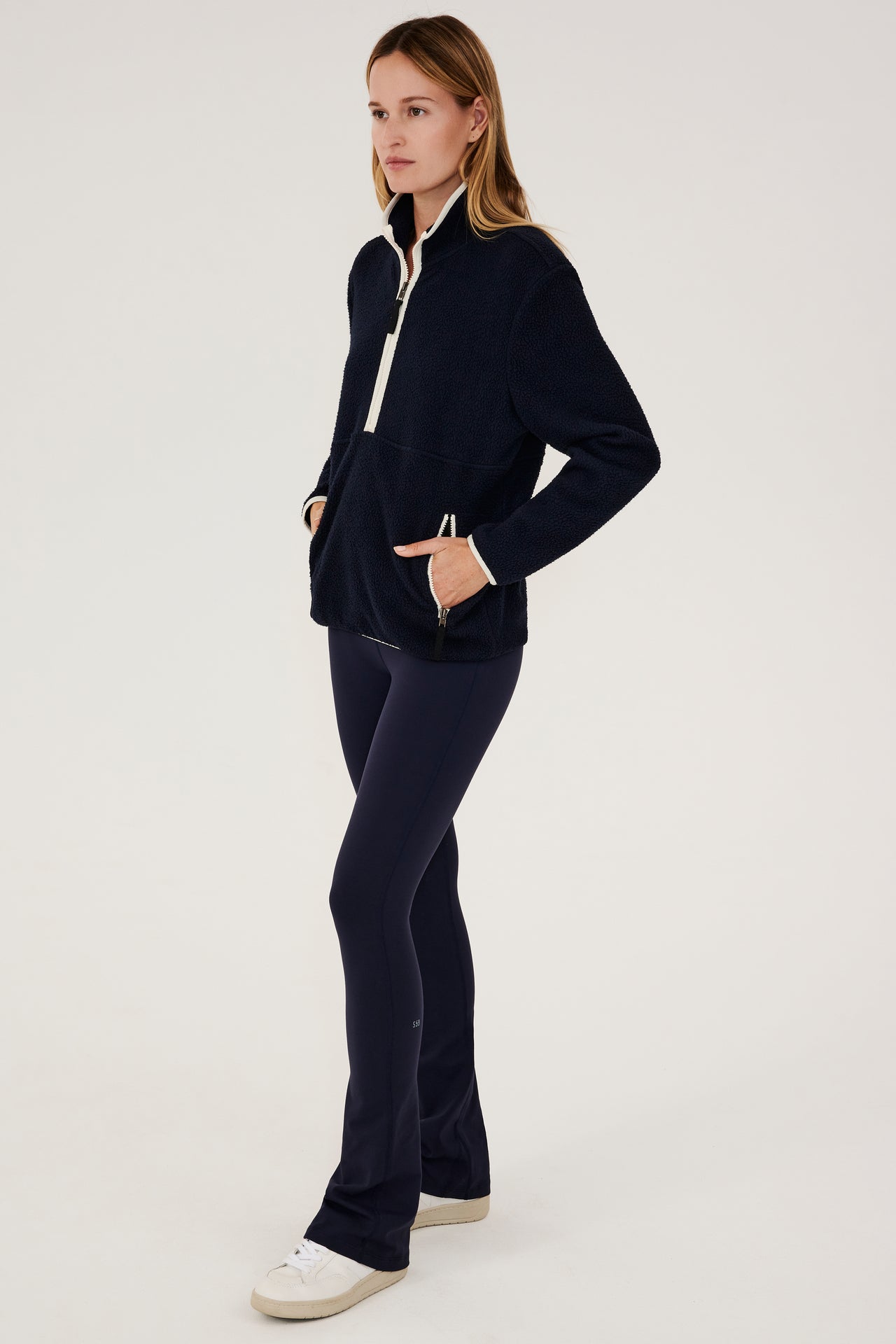 The model is wearing a SPLITS59 Libby Sherpa Half Zip in Indigo/Creme and leggings.