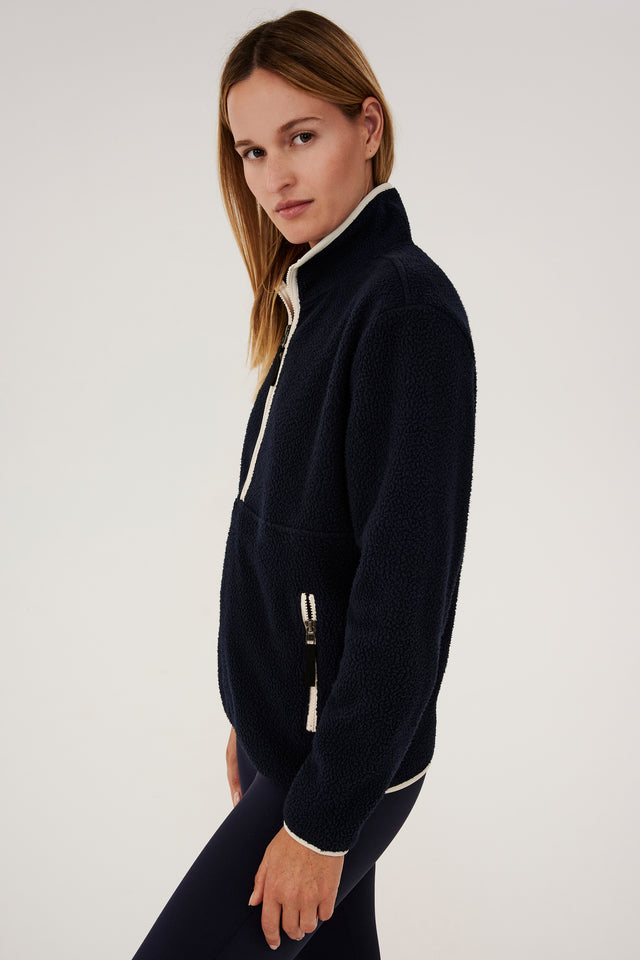 A woman in a black SPLITS59 Libby Sherpa Half Zip - Indigo/Creme jacket.