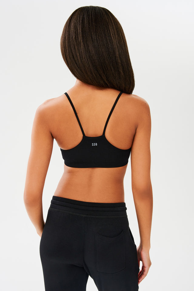 The back view of a woman wearing a Splits59 Loren Seamless Bra in Black, designed with chafe-free fabric, perfect for the gym.