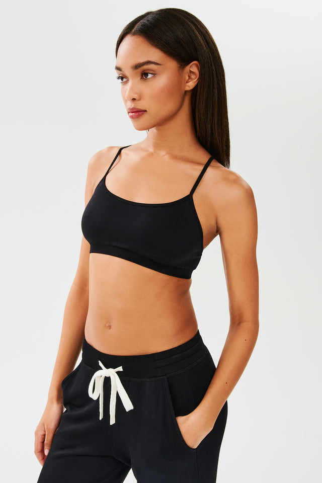 The model is wearing a chafe-free fabric, Splits59 Loren Seamless Bra in Black, and sweatpants designed for the gym.