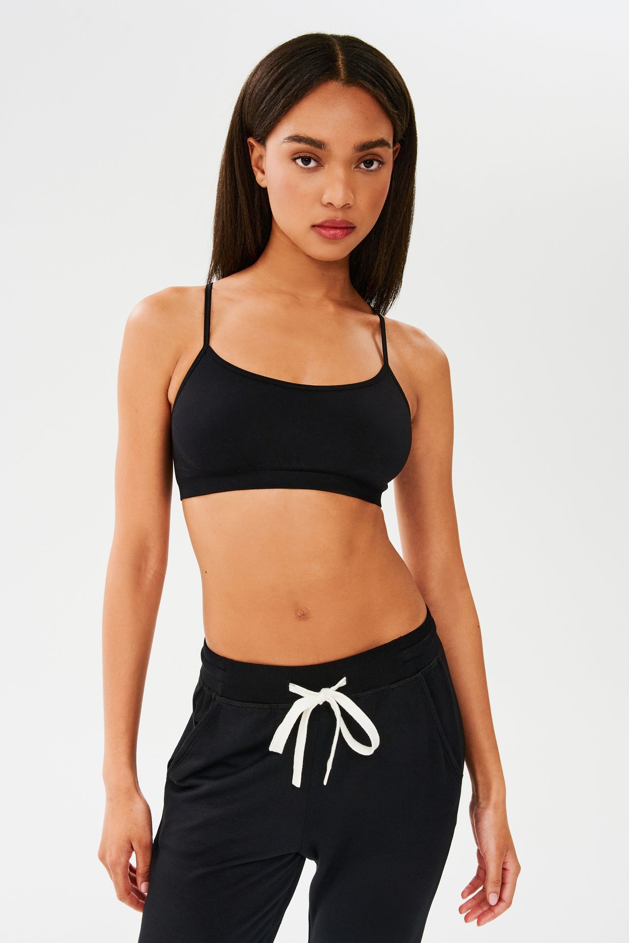 The model is wearing a Splits59 Loren Seamless Bra in Black and sweatpants, designed with chafe-free fabric.
