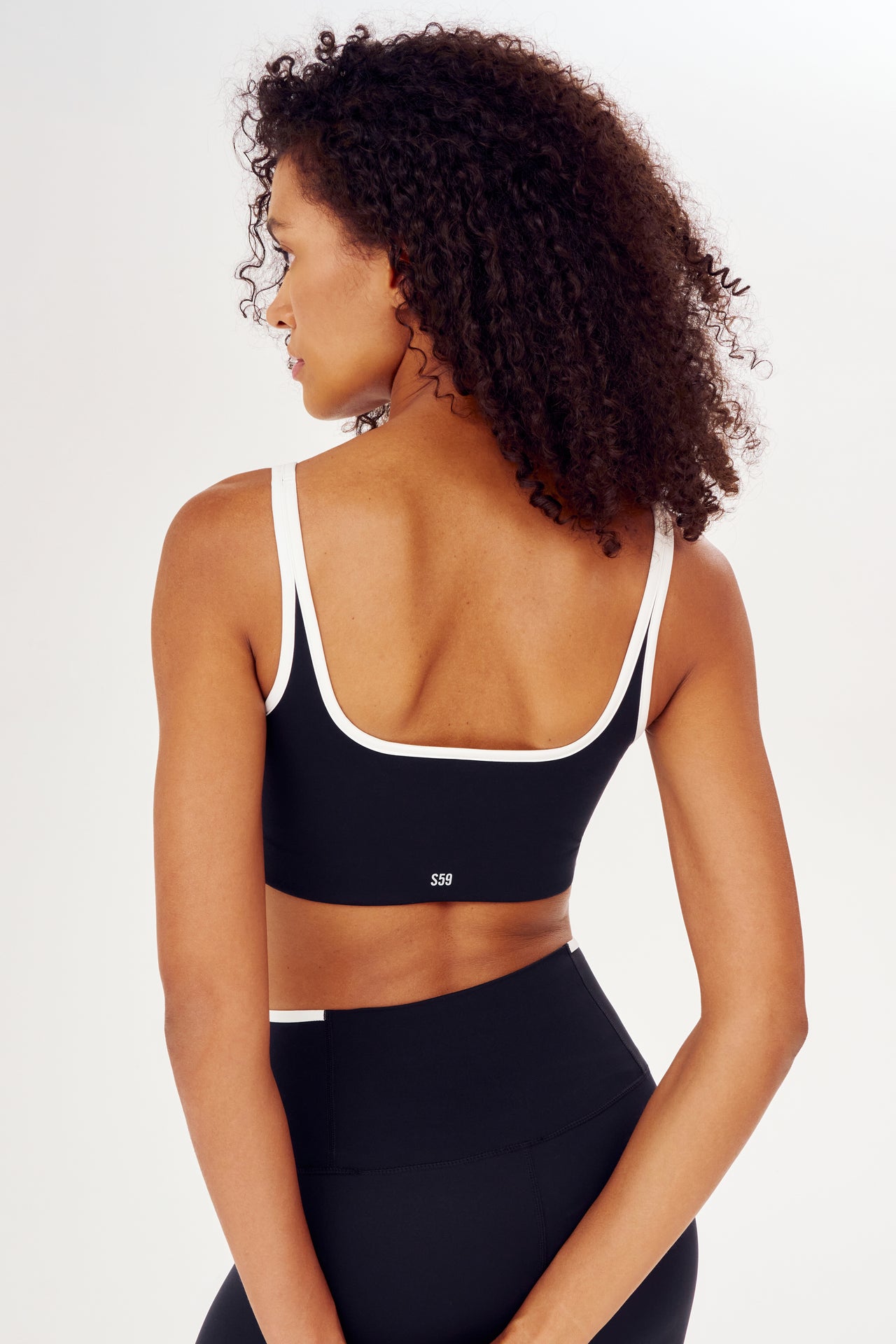 The back view of a woman wearing a SPLITS59 Cait Rigor Bra in Black/White, designed for high impact workouts.