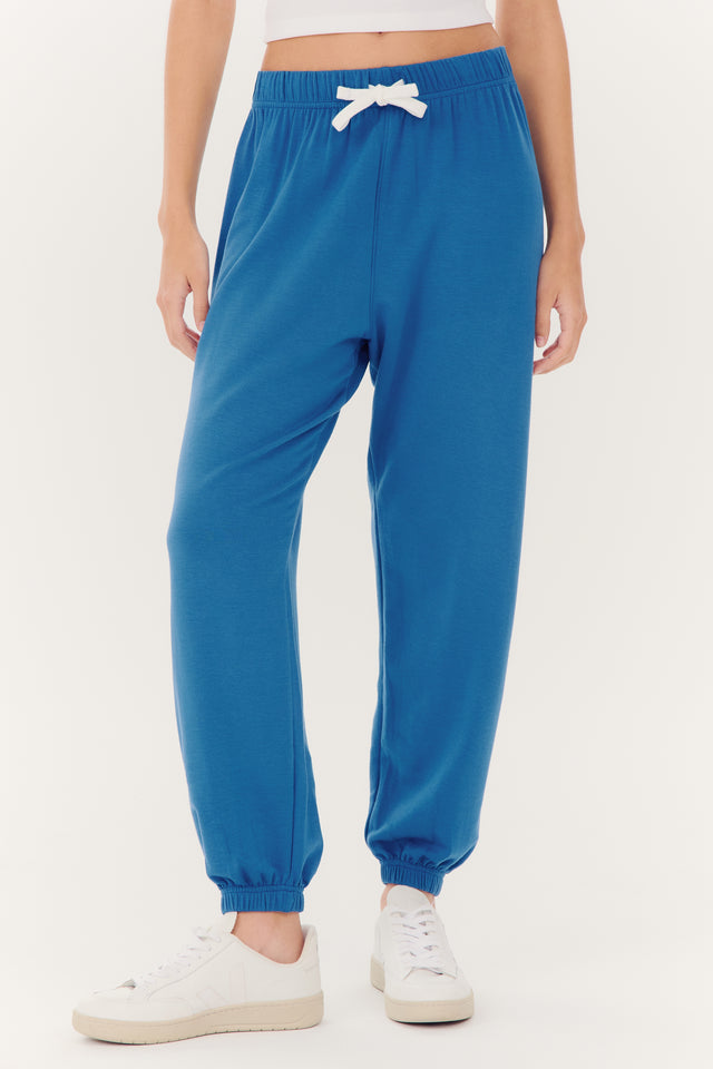 Person wearing SPLITS59 Andie Oversized Fleece Sweatpant in Stone Blue made of modal fabric and white sneakers.
