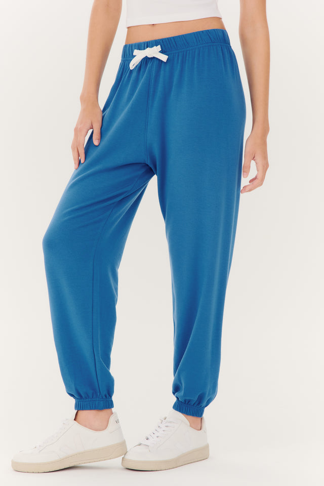Woman wearing SPLITS59 Andie Oversized Fleece Sweatpant in Stone Blue made with spandex fabric and white sneakers.