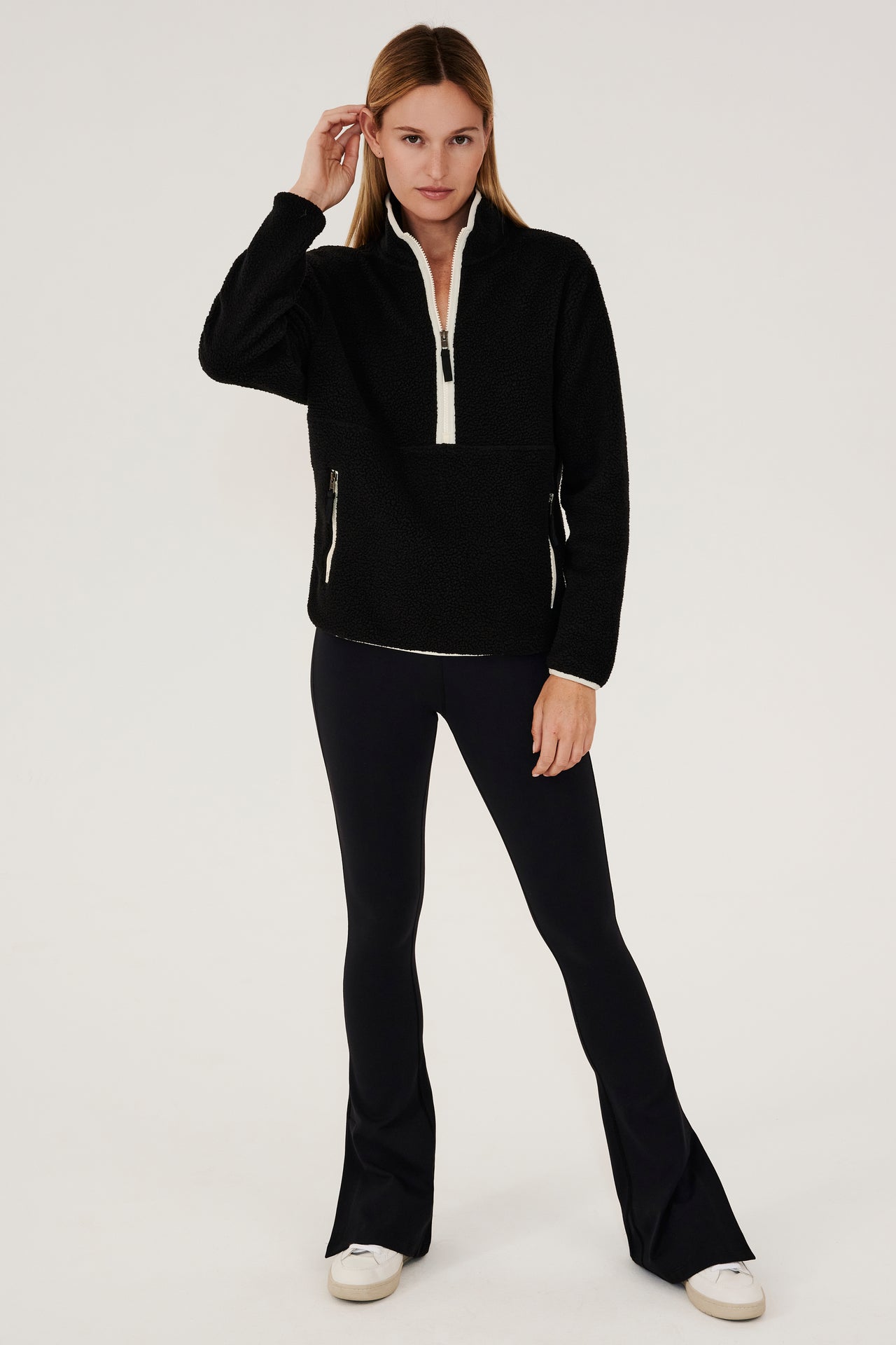 A woman wearing a black SPLITS59 Libby Sherpa Half Zip sweater and leggings.