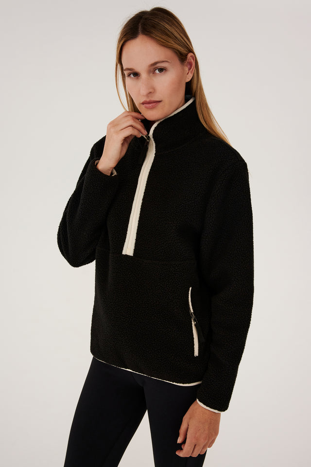 A woman wearing a SPLITS59 Libby Sherpa Half Zip - Black/Creme fleece pullover.