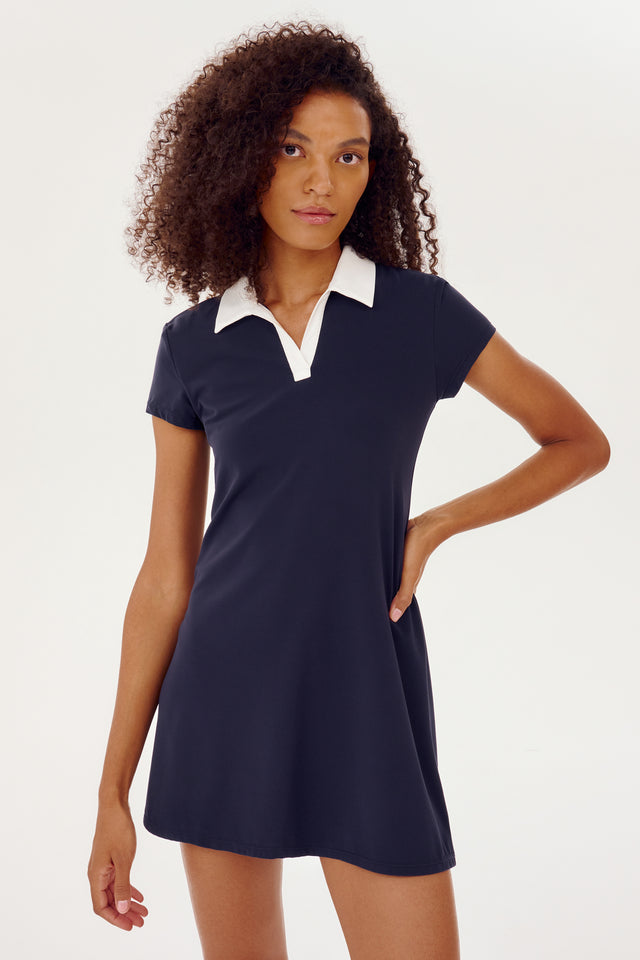 The model is wearing a SPLITS59 Polo Airweight Dress in Indigo with a white collar.