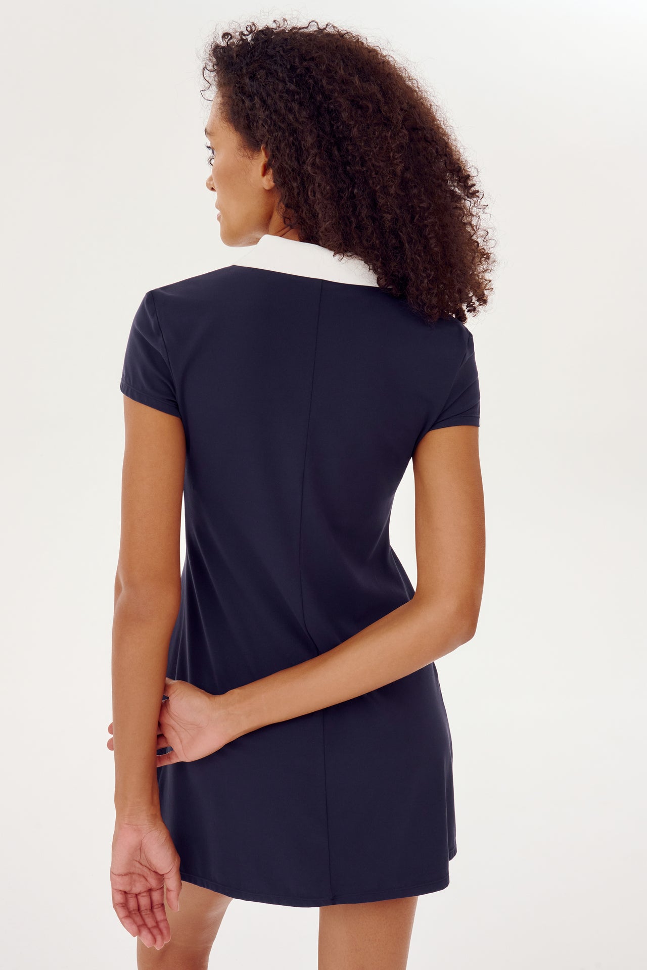 The back view of a woman wearing a SPLITS59 Polo Airweight Dress in Indigo with white collar.