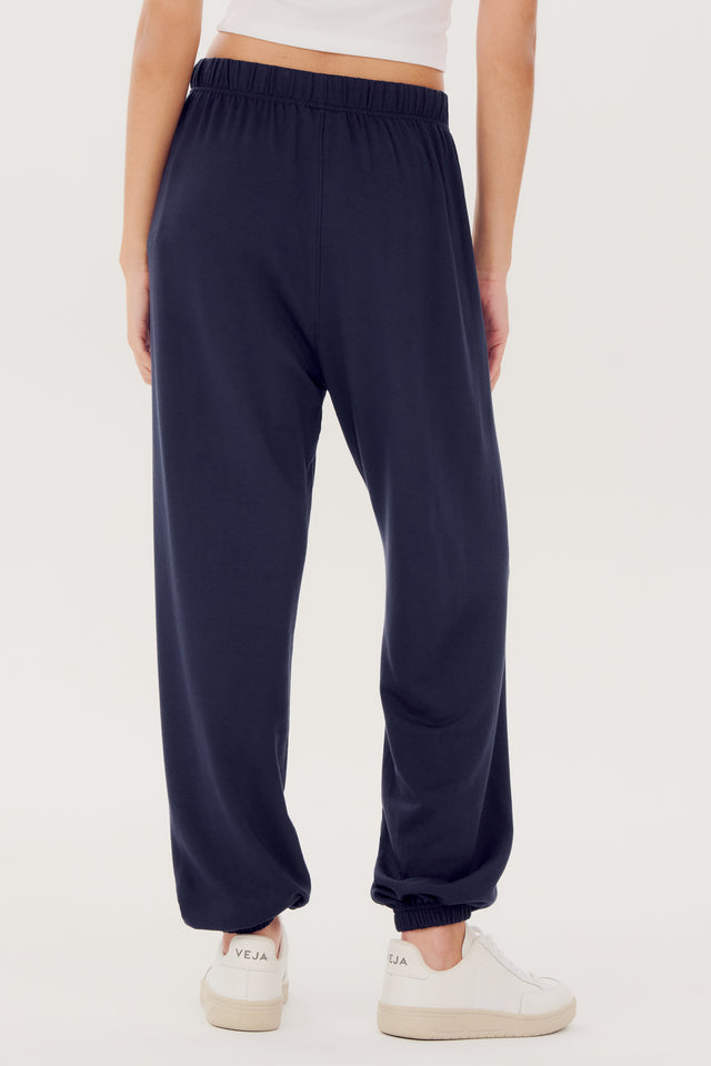 Woman from the waist down wearing SPLITS59 Andie Oversized Fleece Sweatpant - Indigo made of 95% modal fabric and 5% spandex, paired with white sneakers.