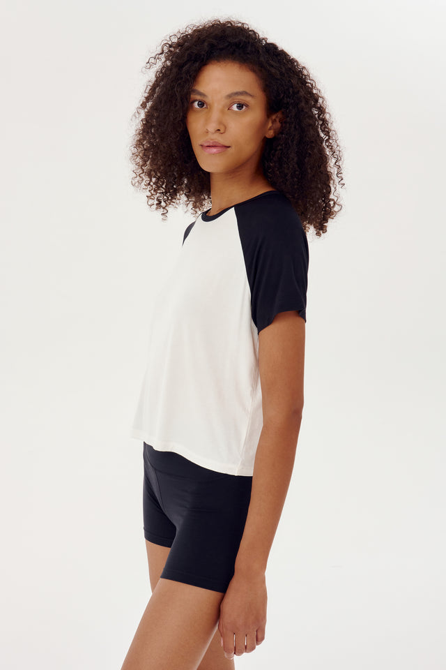 A young girl wearing a SPLITS59 Baseball Jersey Tee in White/Black and shorts.