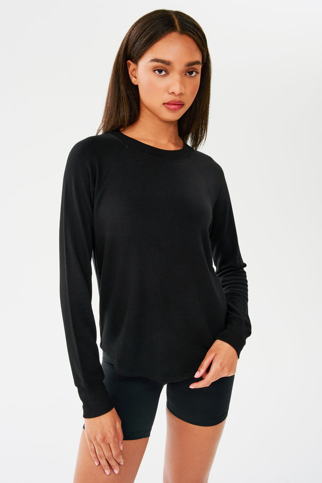 Front shot of woman with dark straight hair, wearing black sweatshirt with black shorts