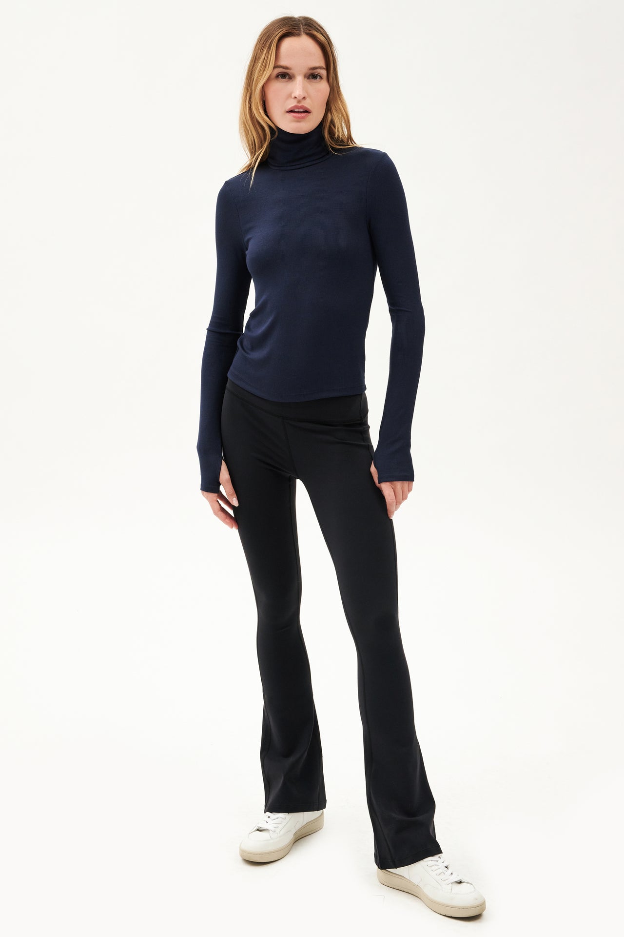 A woman wearing a SPLITS59 Jackson Rib Full Length Turtleneck in Indigo and black leggings for yoga.