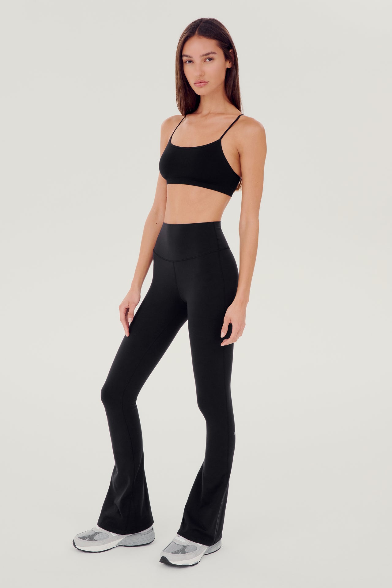 A woman in SPLITS59's Raquel High Waist Flared Legging - Black and black high-waist pants designed for 4-way stretch, perfect for gym workouts.