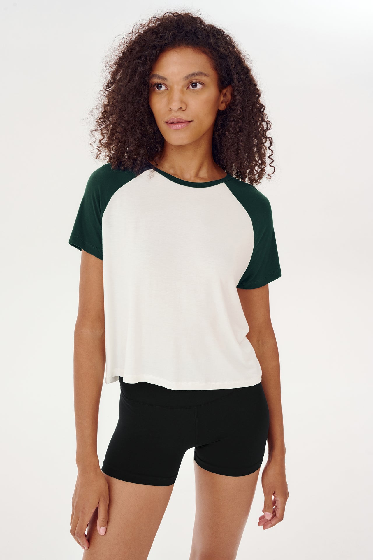 A young woman wearing a SPLITS59 Baseball Jersey Tee in White/Forest fit.
