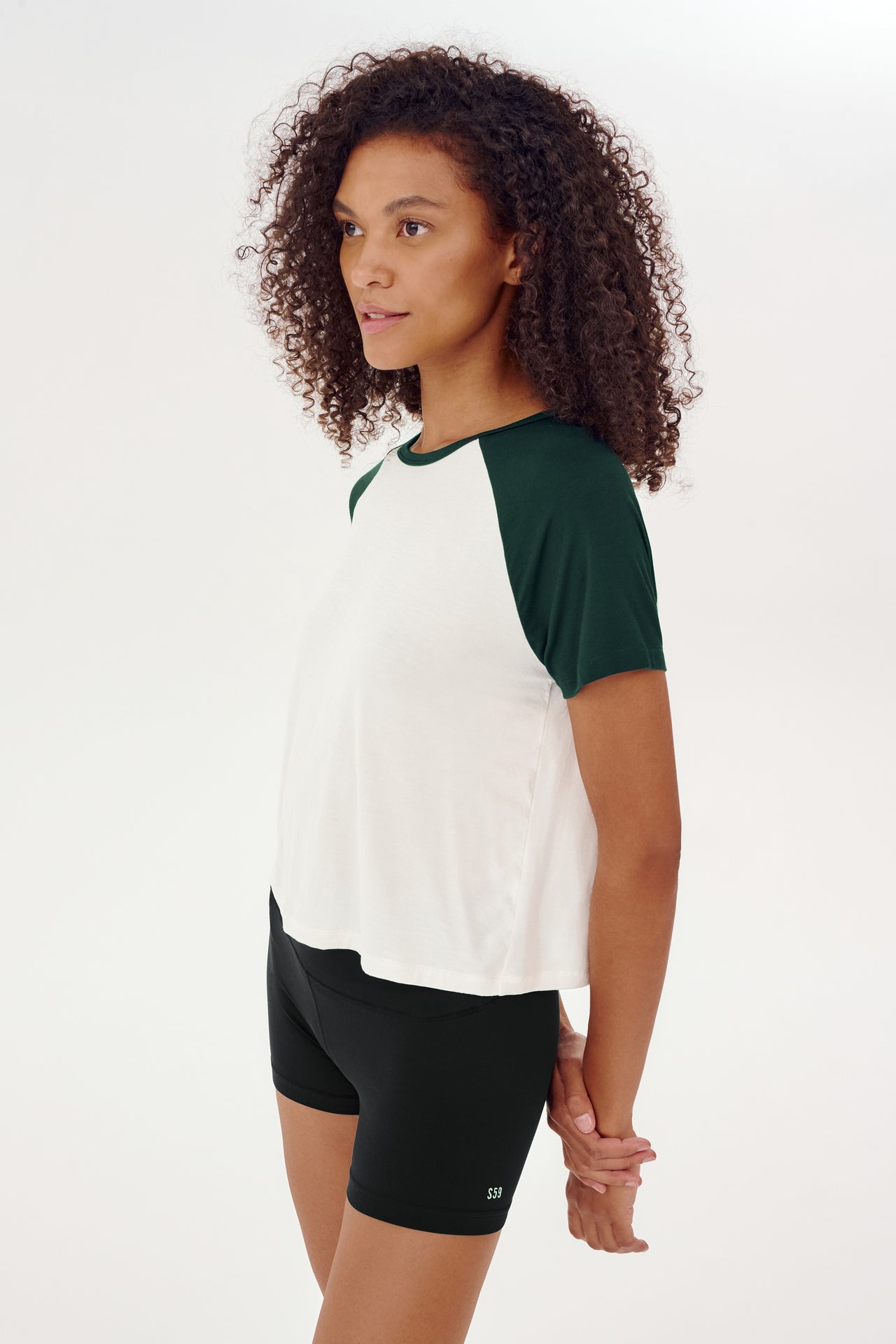 A woman wearing a SPLITS59 white and green Baseball Jersey Tee - White/Forest.