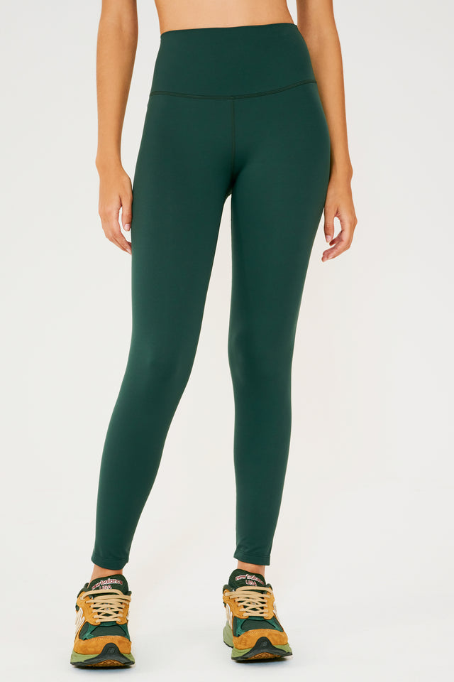 Front view of model wearing dark green high waist  leggings and orange shoes