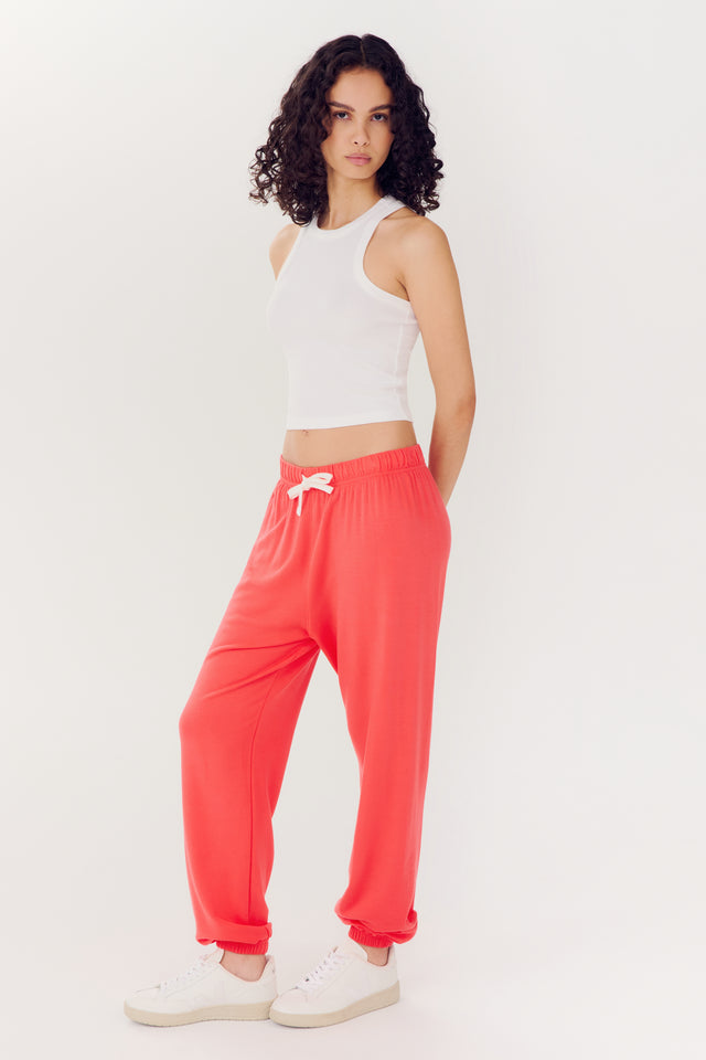 Woman posing in white top and Andie Oversized Fleece Sweatpant - Melon made from modal spandex blend against a white background by SPLITS59.
