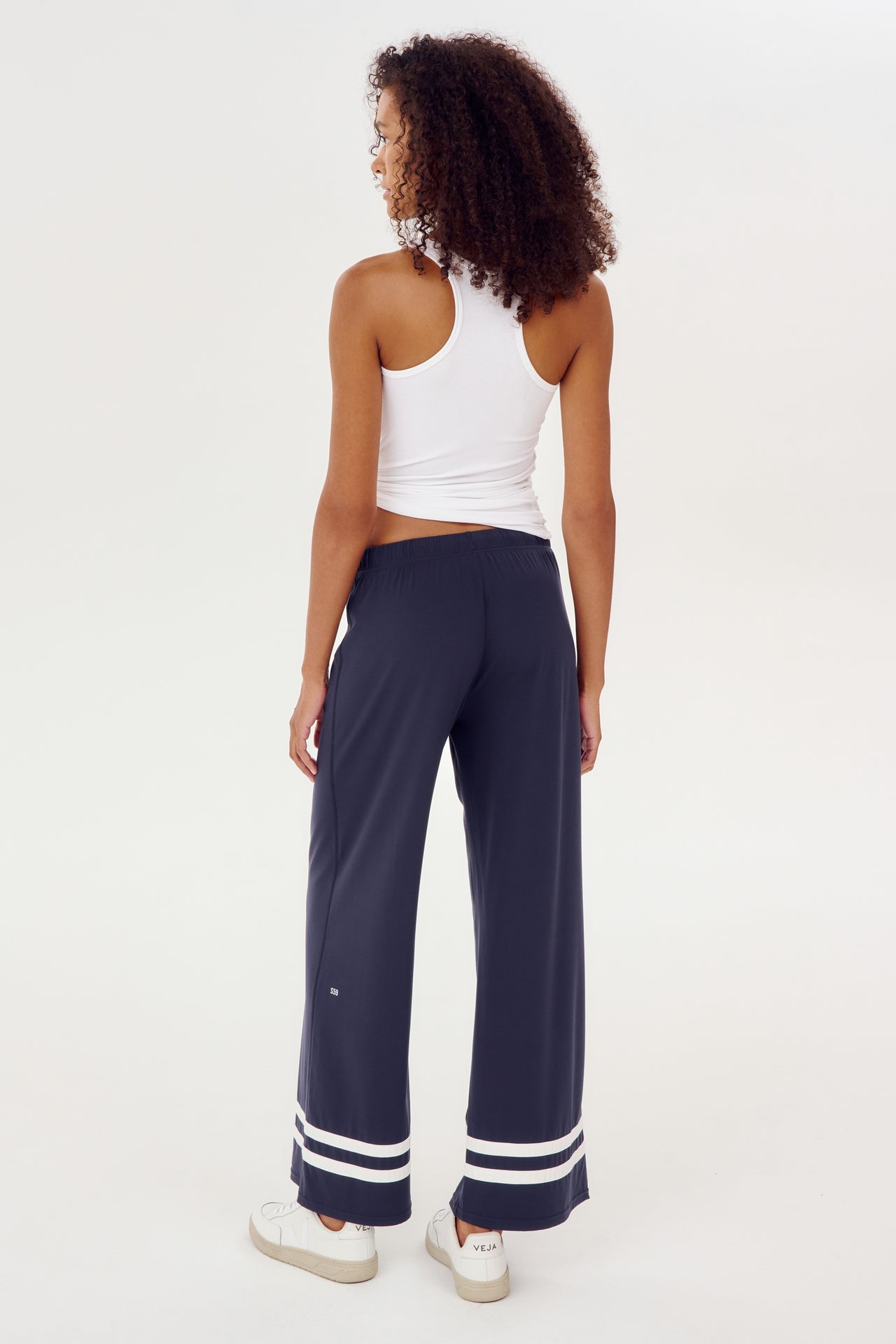 The back view of a woman wearing SPLITS59 Quinn Airweight Wide Leg Pant in Indigo.