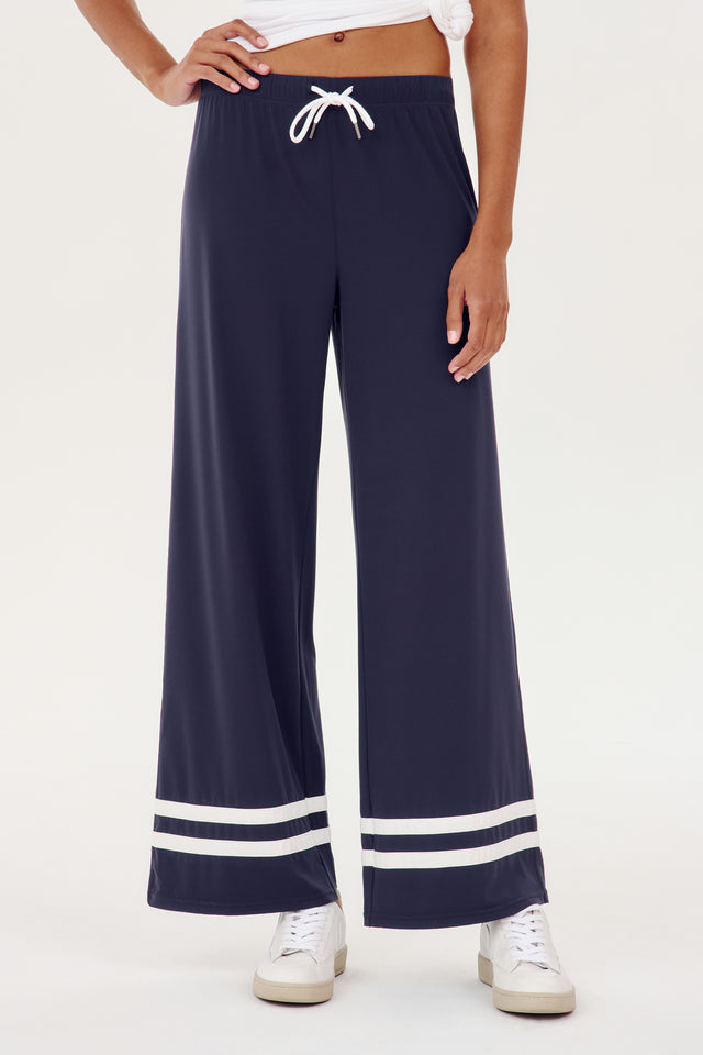 A woman wearing a SPLITS59 Quinn Airweight Wide Leg Pant in Indigo with white stripes for yoga comfort.