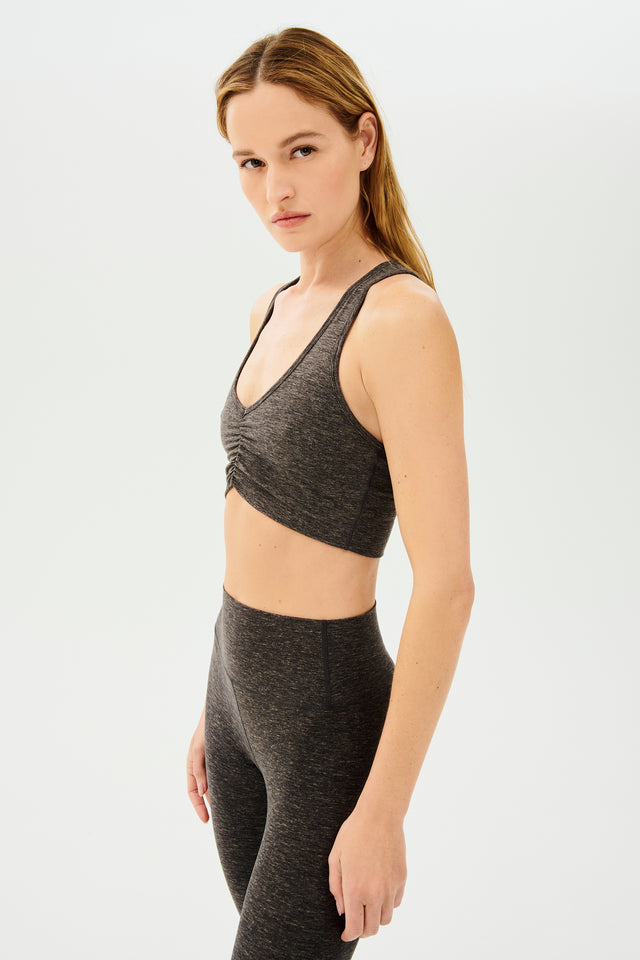 Side view of girl wearing scrunched sports bra in grey with grey bike shorts