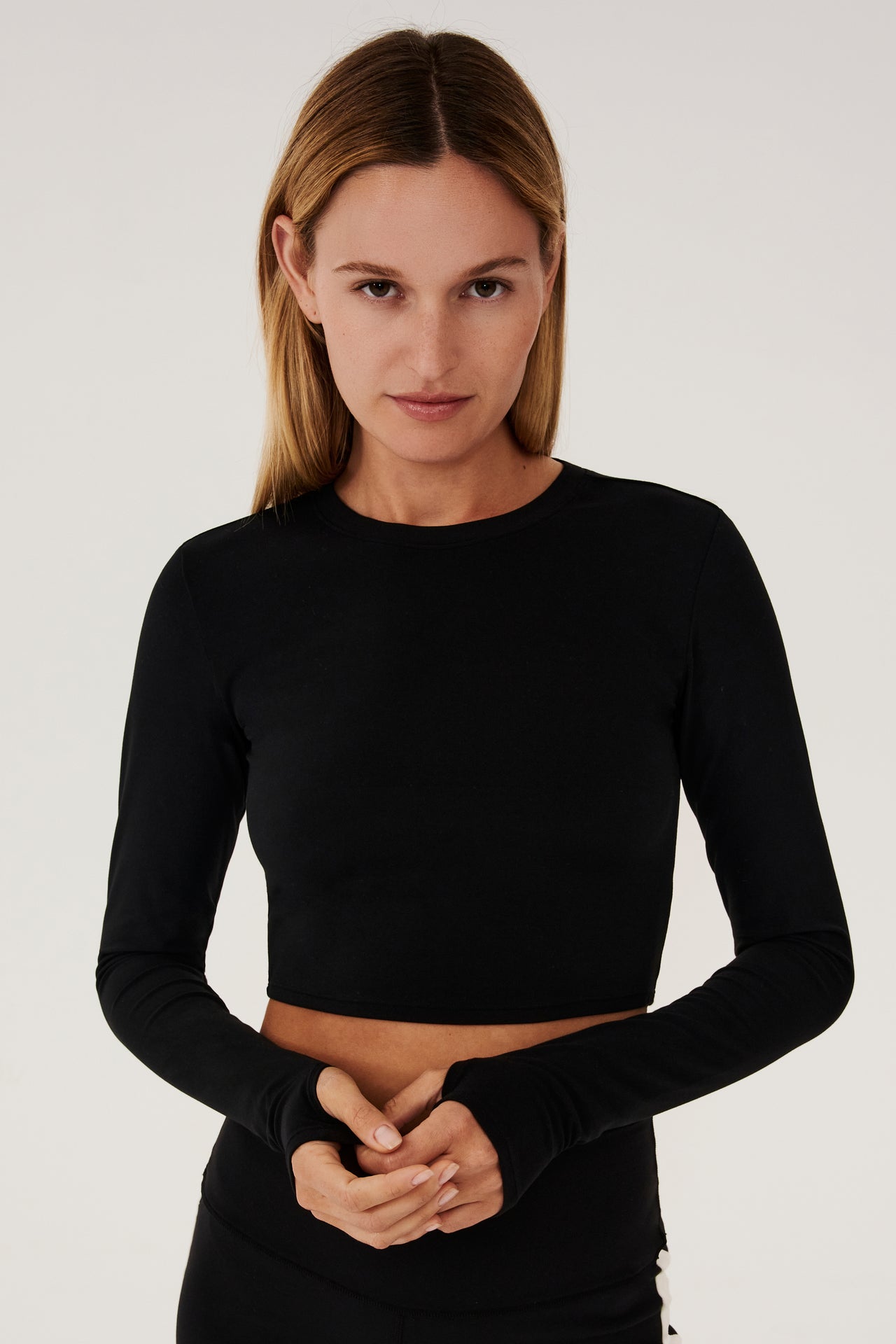 Front view of girl wearing black long sleeve crop top and black leggings with white stripe