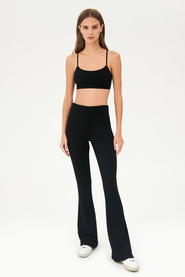 The model is wearing a black Raquel Fleece Flare crop top and flared pants from SPLITS59.