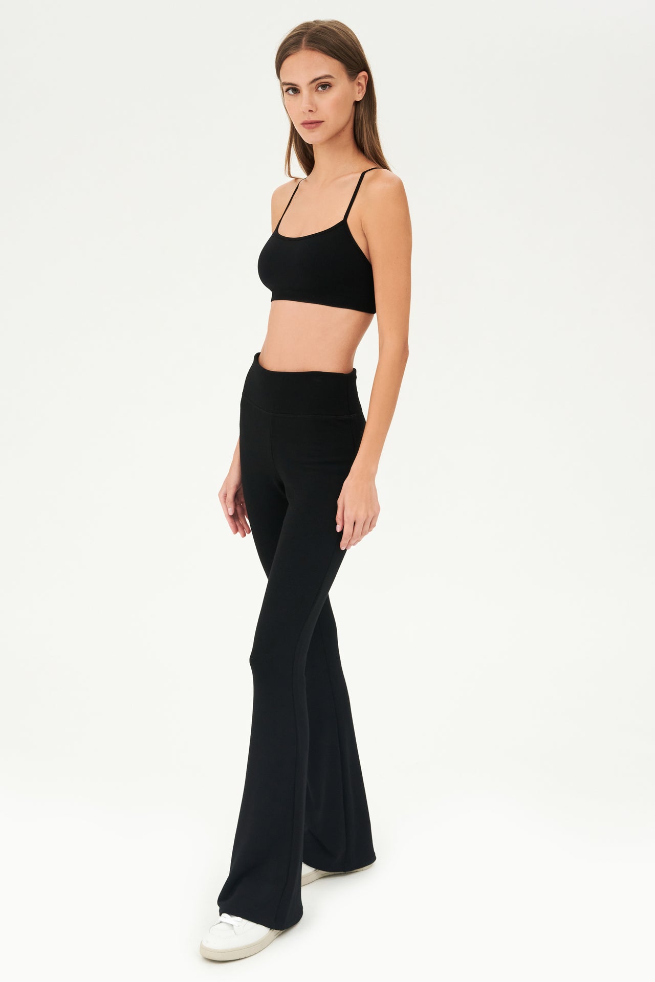The model is wearing a cozy black crop top and SPLITS59 Raquel Fleece Flare - Black pants.