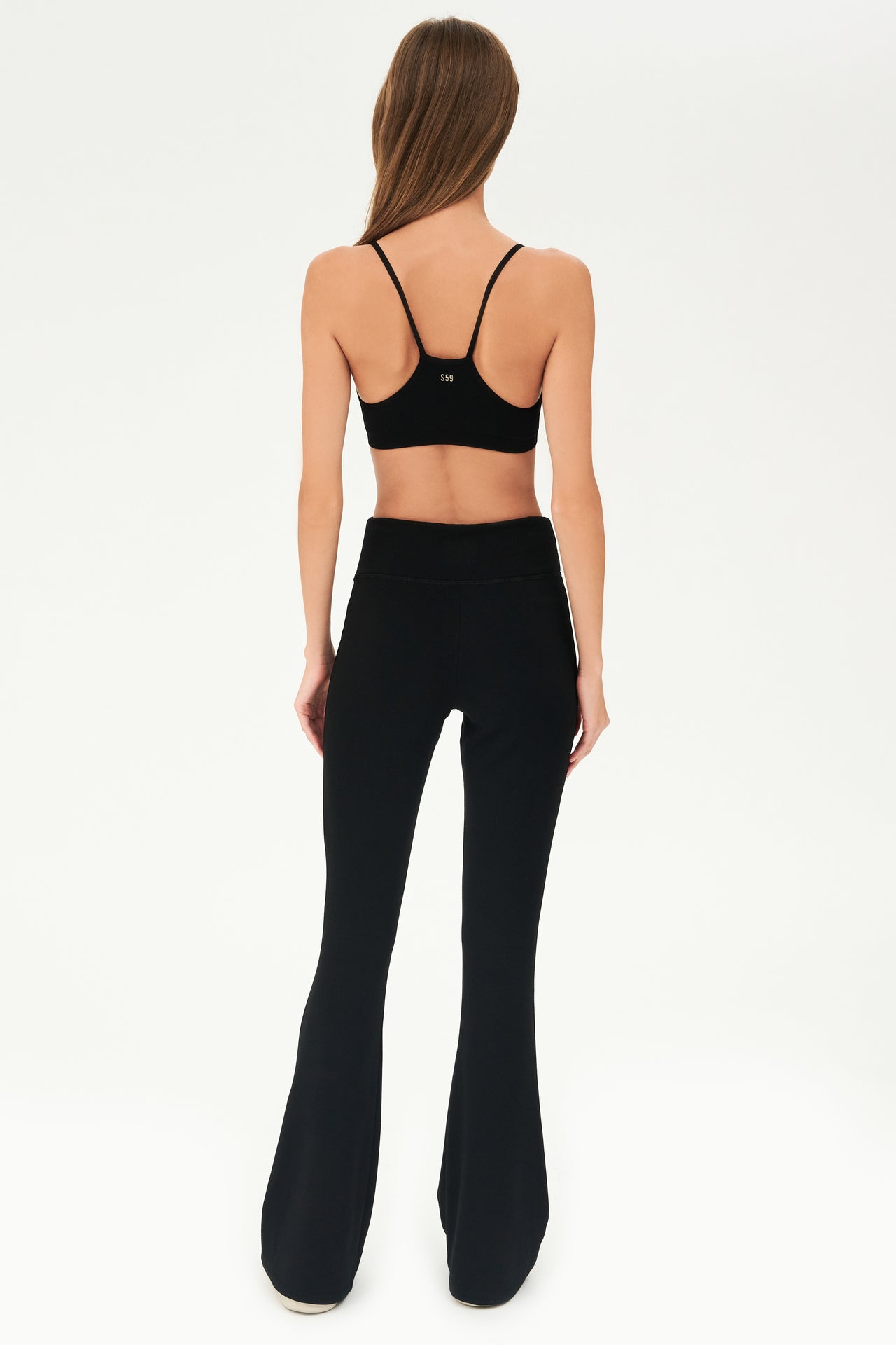 The back view of a woman wearing SPLITS59 Raquel Fleece Flare - Black leggings.