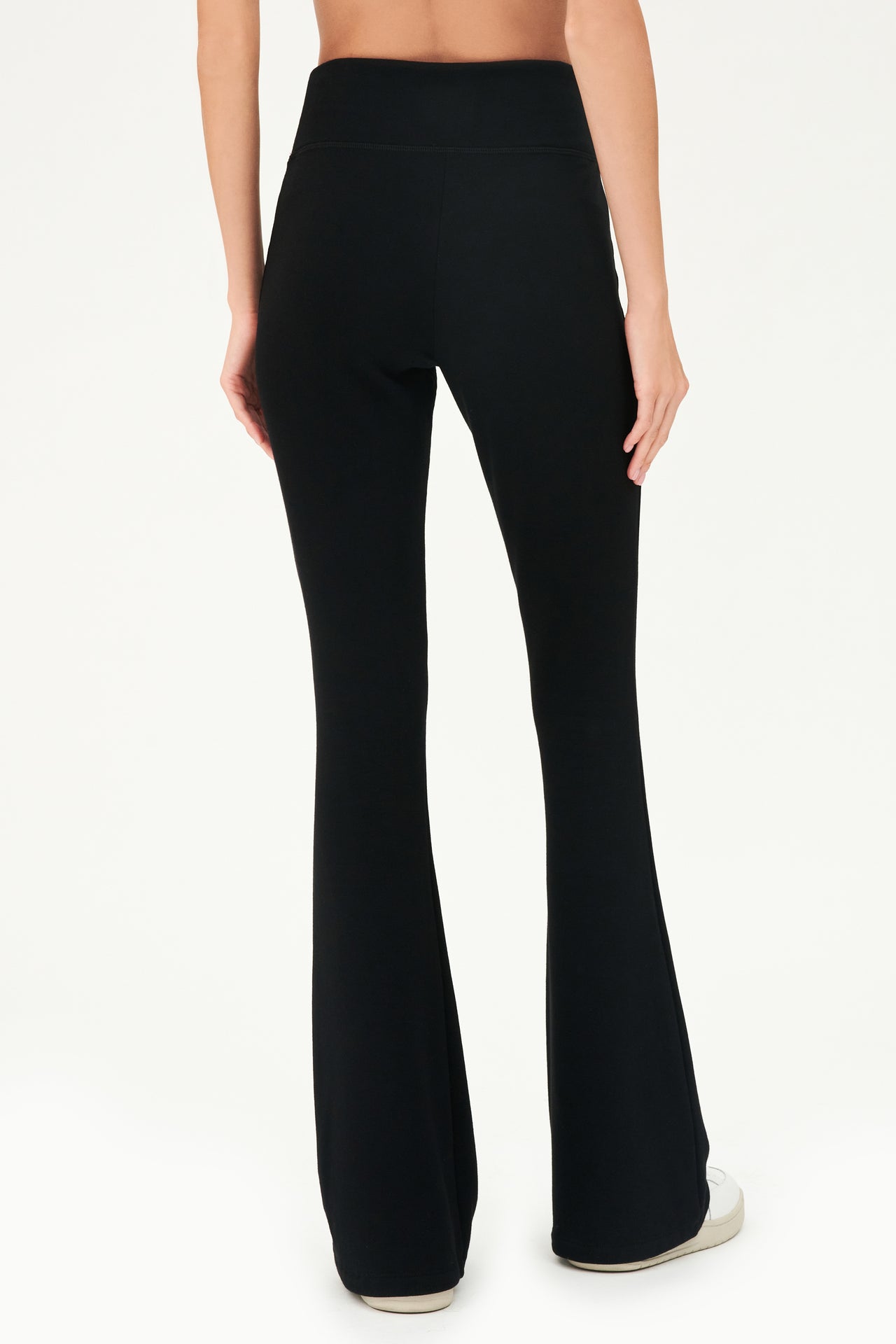The back view of a woman wearing cozy, black SPLITS59 Raquel Fleece Flare pants.