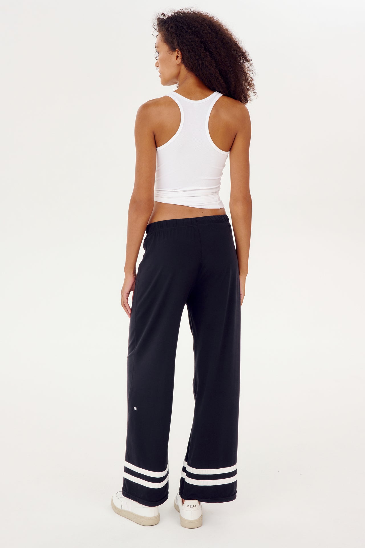 The back view of a woman wearing black and white SPLITS59 Quinn Airweight Wide Leg Pants, designed for comfort and workout.