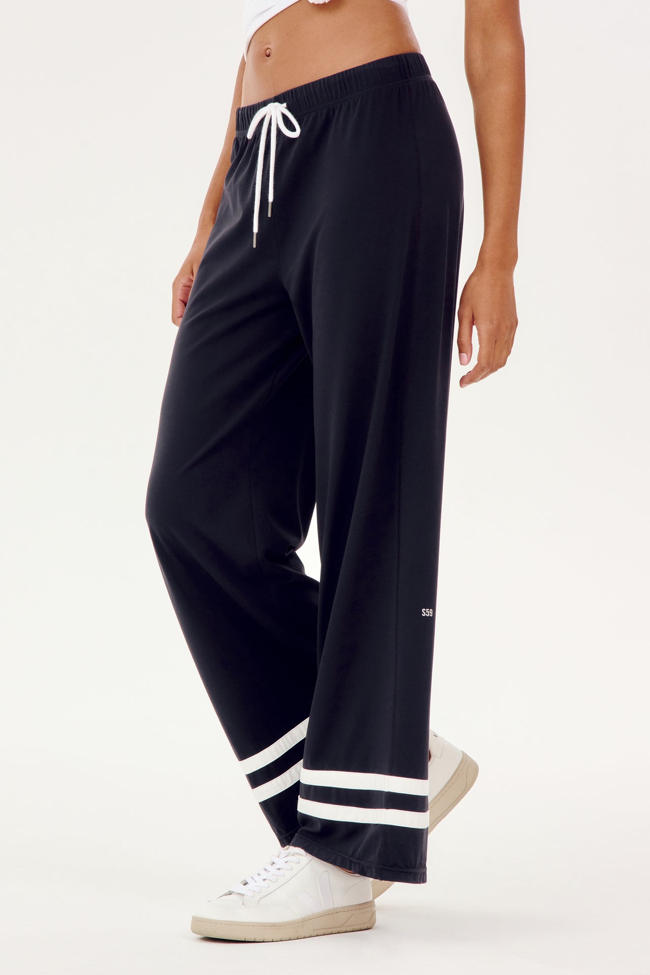 A woman wearing black SPLITS59 Quinn Airweight Wide Leg Pants with white stripes for comfort during her workout.