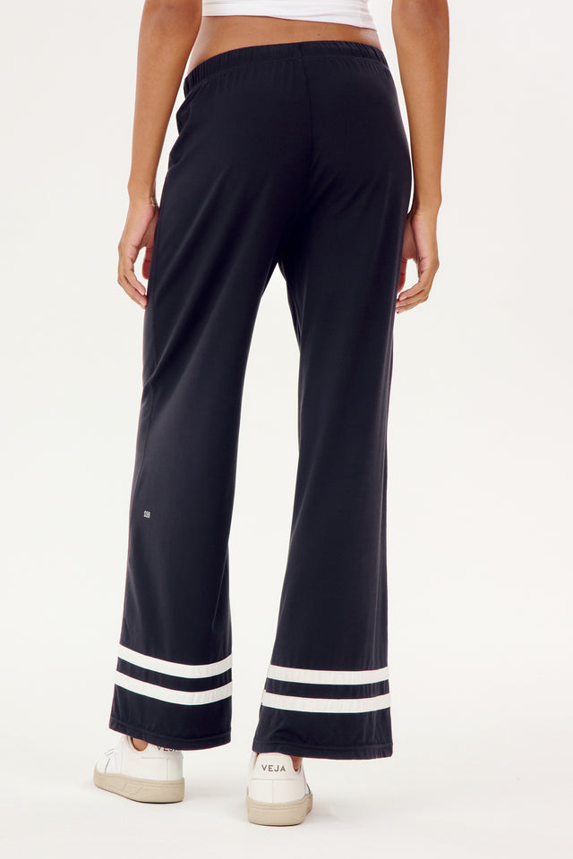 The back view of a woman wearing black and white stripe SPLITS59 Quinn Airweight Wide Leg Pant leggings, ideal for comfort during a workout.