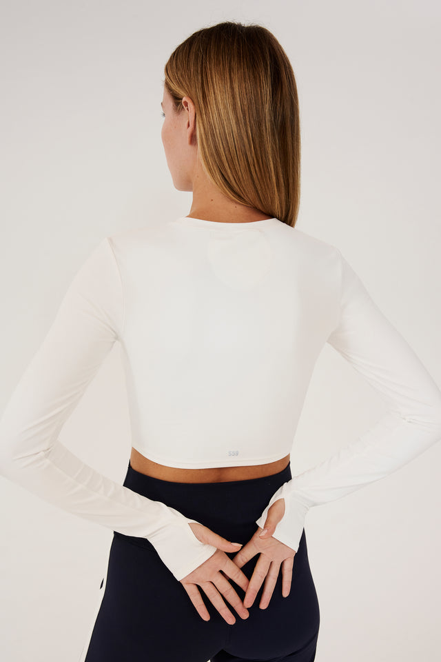 Back view of girl wearing white long sleeve crop top and black leggings with white stripe 