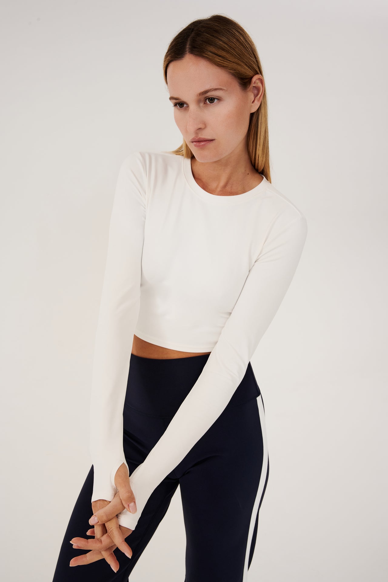 Front view of girl wearing white long sleeve crop top and black leggings with white stripe 
