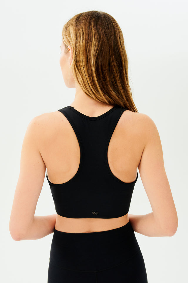 Back view of girl wearing black sports bra and black leggings