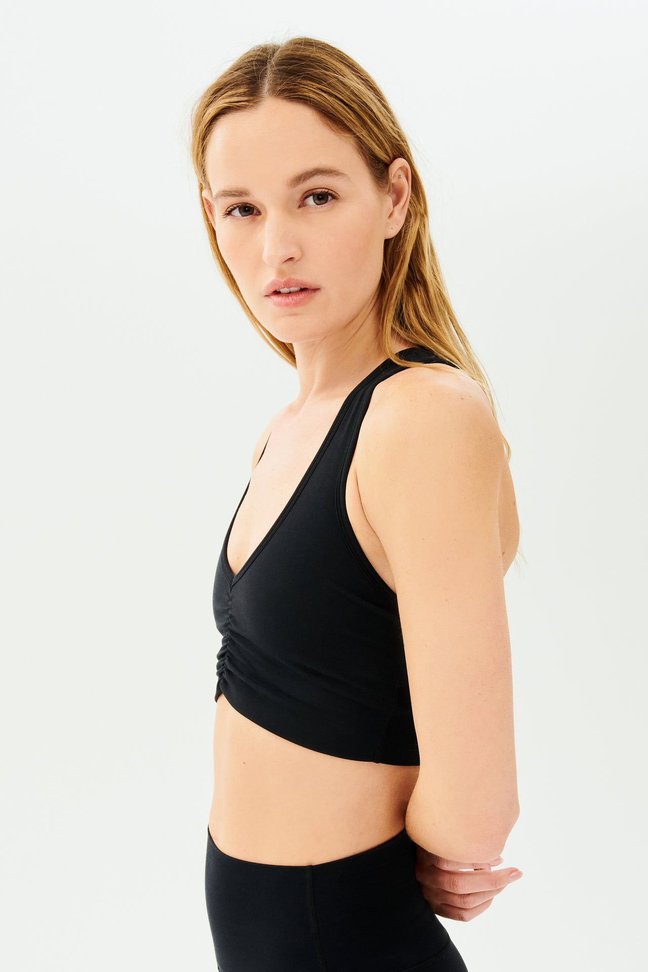 Side view of girl wearing black sports bra with scrunch and black leggings