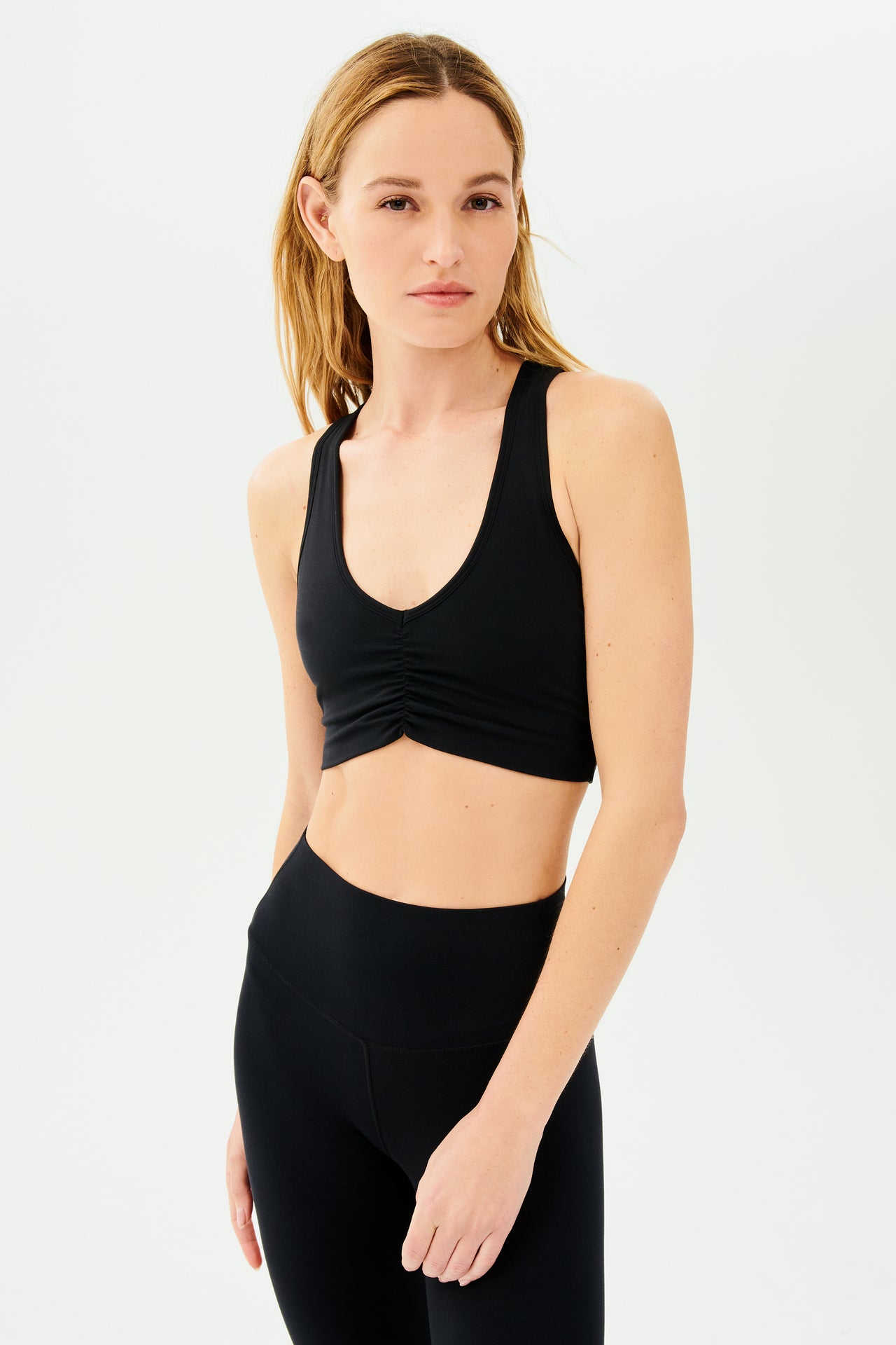 Front view of girl wearing black sports bra with scrunch and black leggings
