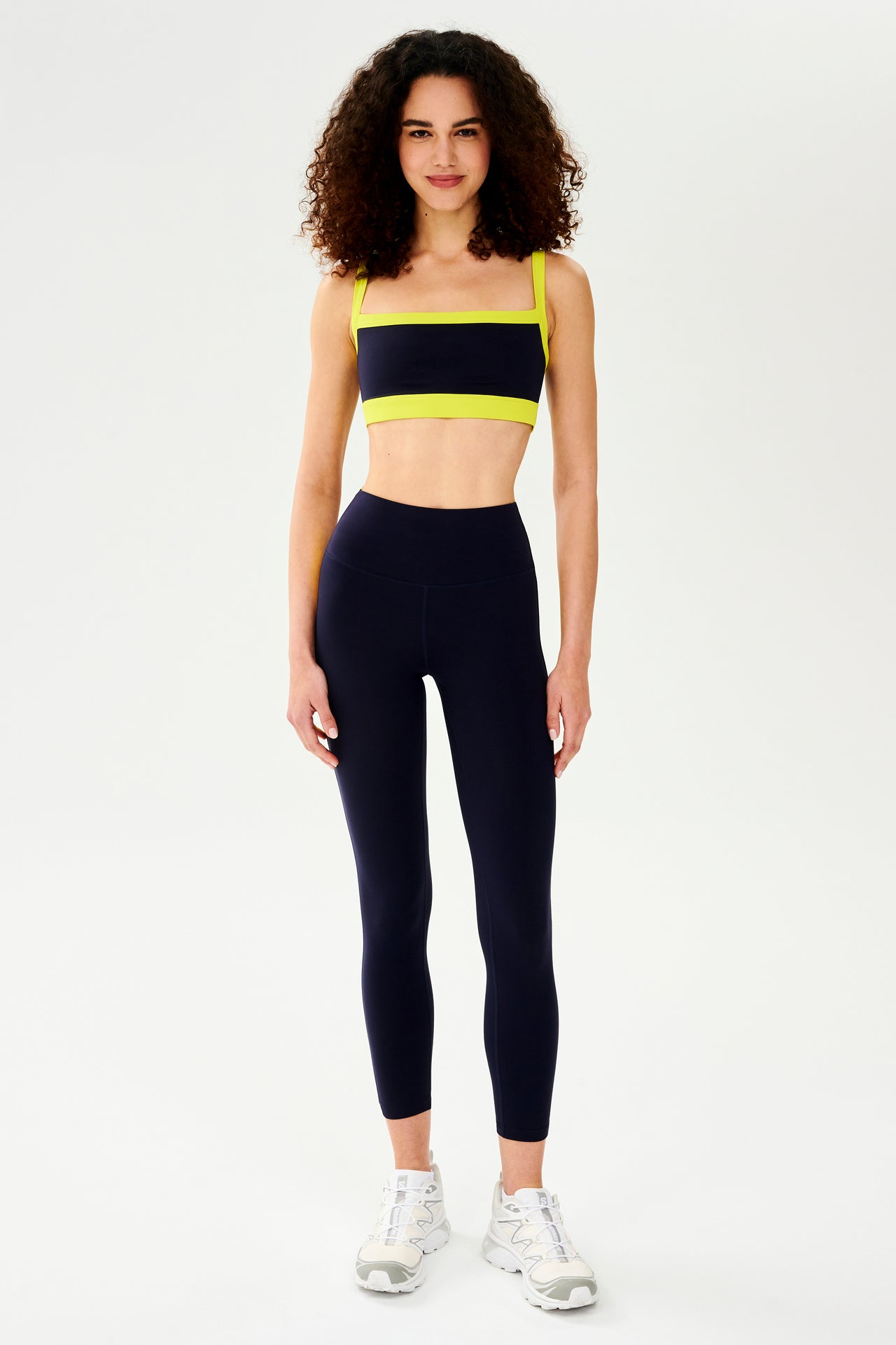 A woman wearing a black and neon Monah Rigor Bra - Indigo/Chartreuse sports bra and leggings designed for comfort and support during a workout by SPLITS59.