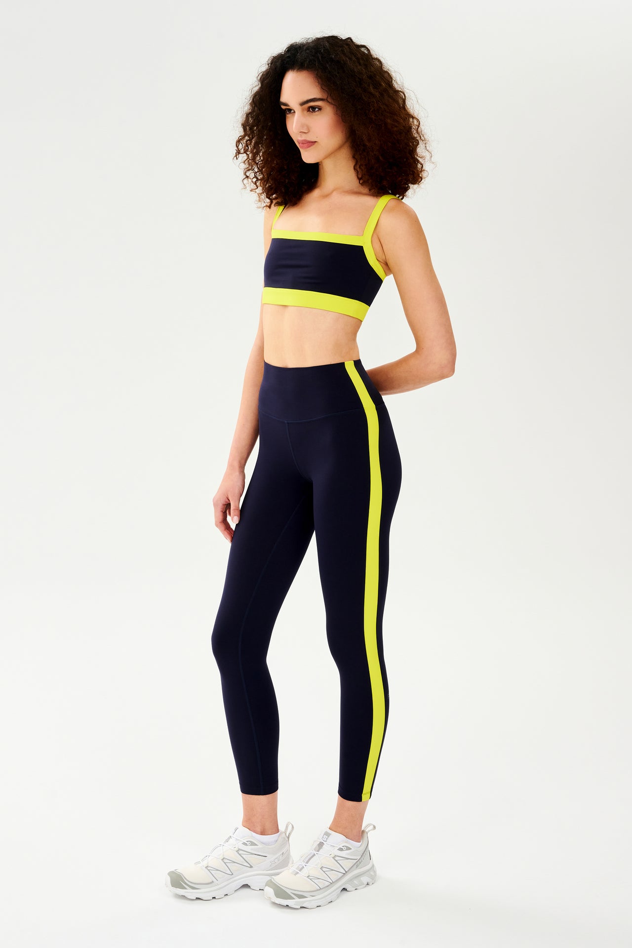 A woman wearing a Monah Rigor Bra in Indigo/Chartreuse and leggings designed for workout comfort and support by SPLITS59.