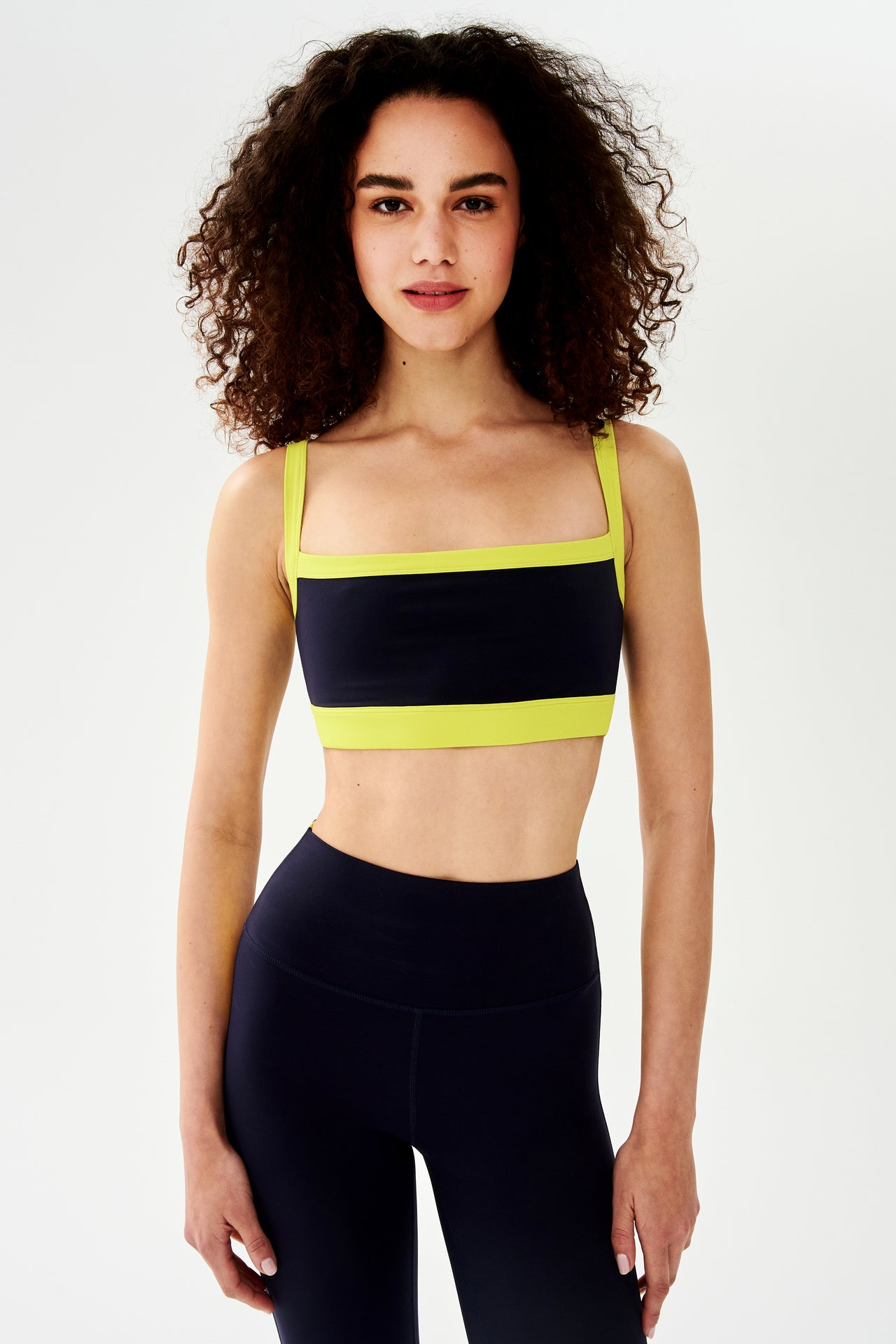 The model is wearing a Monah Rigor Bra in Indigo/Chartreuse, designed by SPLITS59 for comfort and support during workouts.